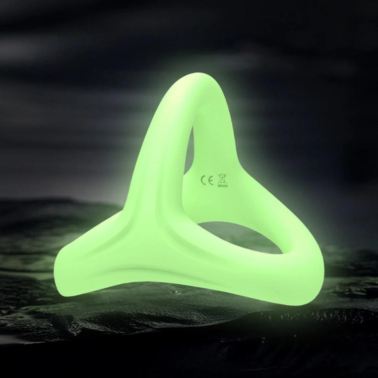 Neon green three-lobed silicone cock ring glowing on a dark textured surface