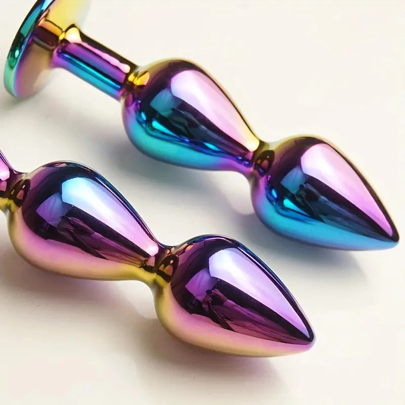 Close-up of two iridescent metallic anal plugs with rounded bulbs and flared bases