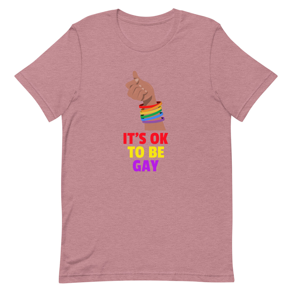 Dusty rose T-shirt with a raised hand wearing rainbow wristbands above “IT’S OK TO BE GAY” text