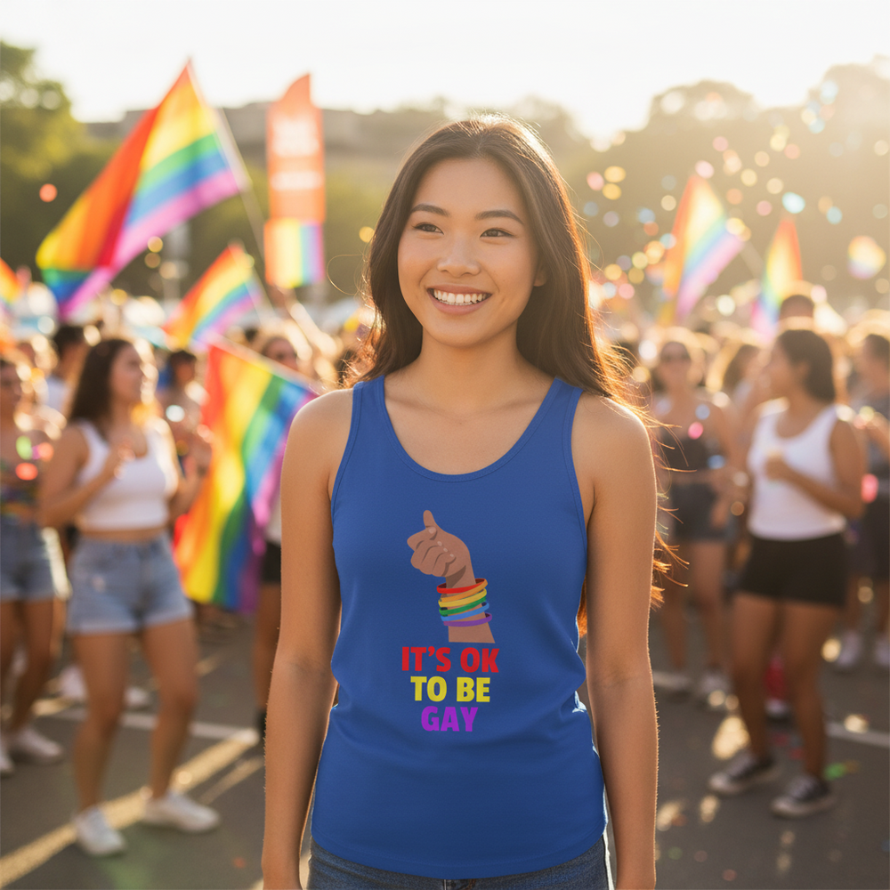 It's Ok to Be Gay unisex tank top worn by a smiling person with rainbow bracelets, surrounded by pride flags and balloons