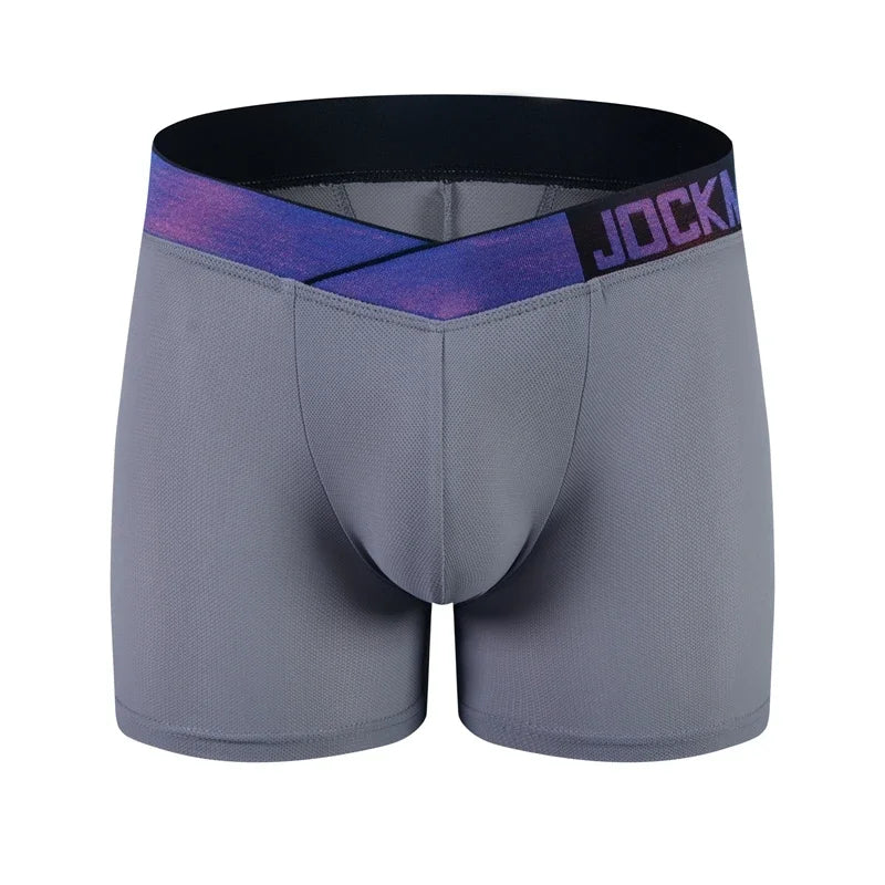A muscular man with long hair poses confidently in Jockmail Mesh Magic Butt-Lifting Boxers, reflected in mirrors under purple light.