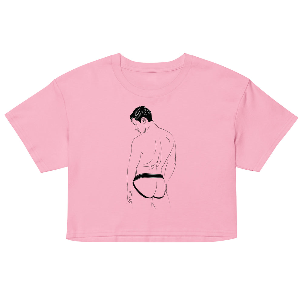 A man in a nightclub wears the Jockstrap Crop Top, a pink, playful design celebrating queer identity, featuring a line drawing of a man's back.
