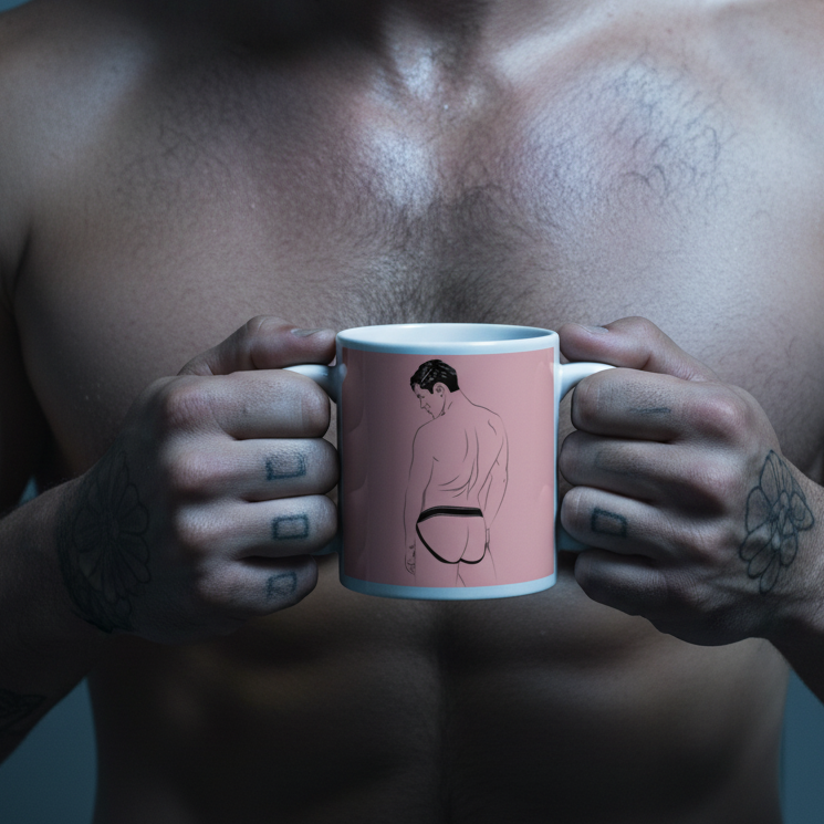 Shirtless tattooed person holds a pink mug showing a line drawing of a person in a jockstrap