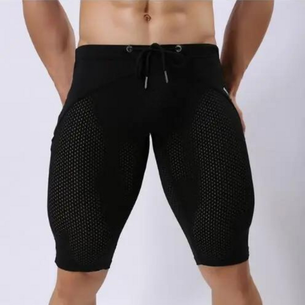 Front view of a model wearing black knee-length shorts with large mesh panels and a drawstring waist