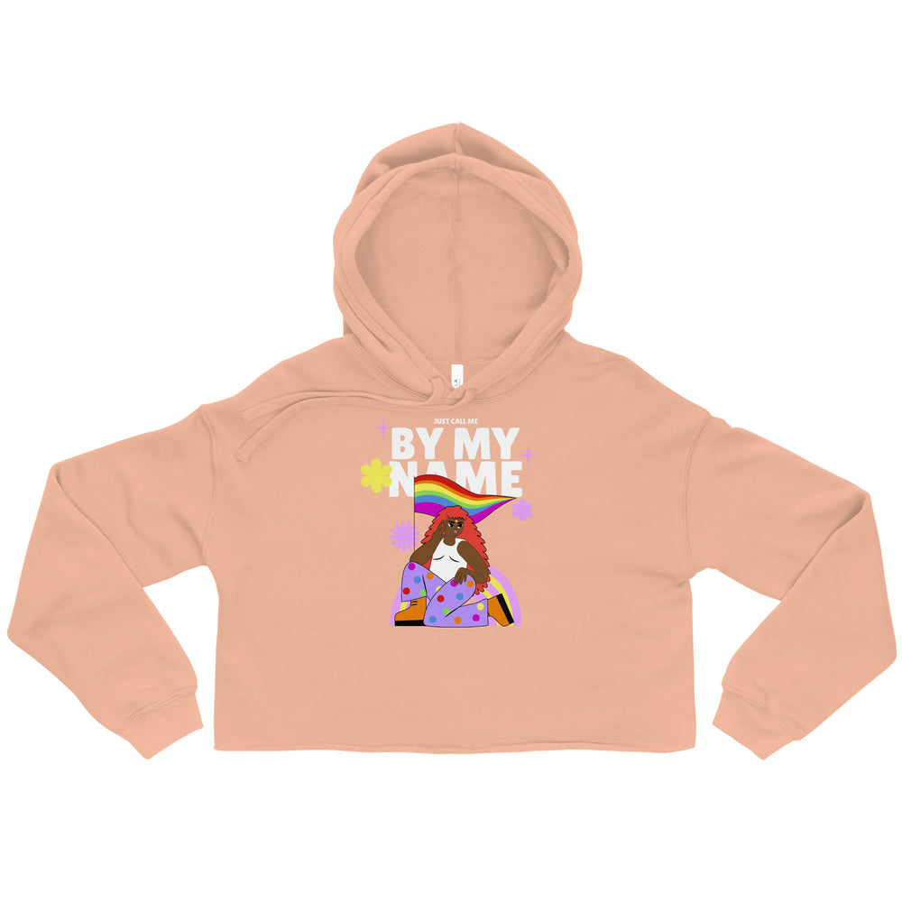 Front-view peach cropped hoodie with “JUST CALL ME BY MY NAME” graphic and rainbow illustration
