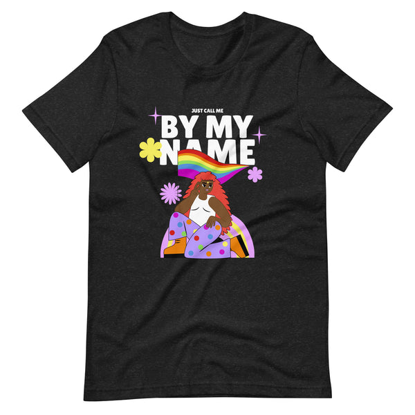 Front view of a black T-shirt reading “Just Call Me By My Name,” with a rainbow and illustrated woman