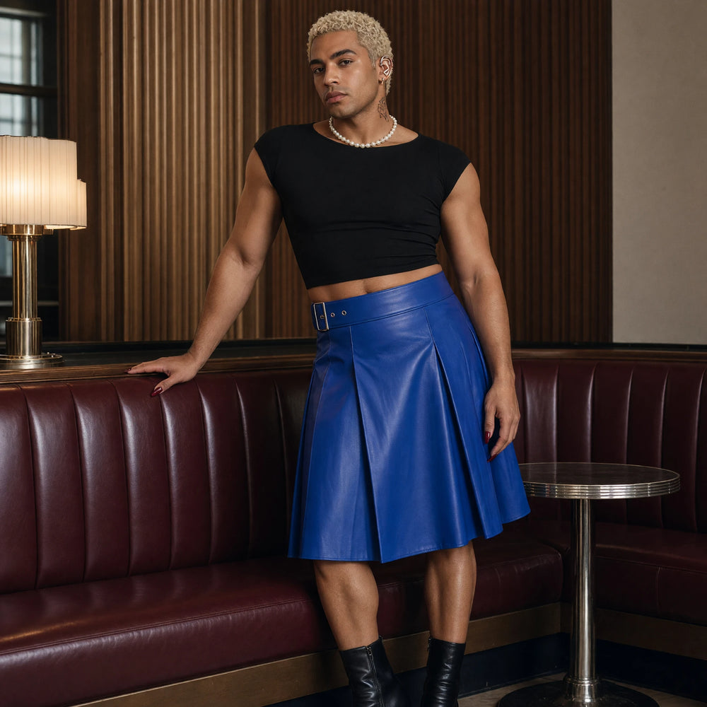 Model wearing a cobalt blue leather-look pleated kilt with a black crop top and pearls in an Art Deco lounge