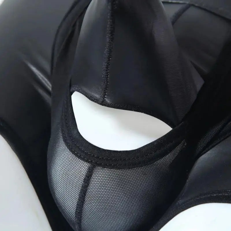 Close-up of black leather-look boxers with a sheer mesh panel and curved cutout