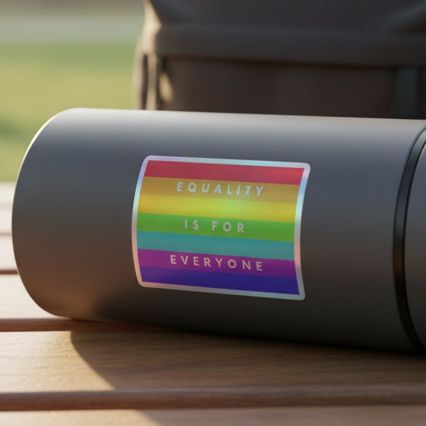 Matte gray bottle on bench, rocking a bold "Equality Is For Everyone" holographic sticker; soft blur queer outdoor vibe.