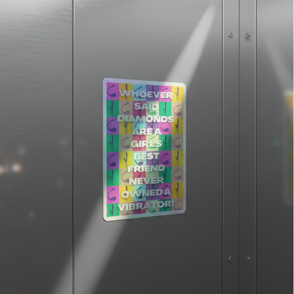 Holographic "Never Owned A Vibrator" sticker on gray metal, shining in sunlight with: “Whoever said diamonds are a girl’s best friend never owned a vibrator.”.