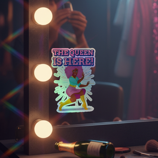 The Queen Is Here Holographic Stickers"—rainbow decals of a bold winged woman on a lit mirror, shown with makeup and champagne.