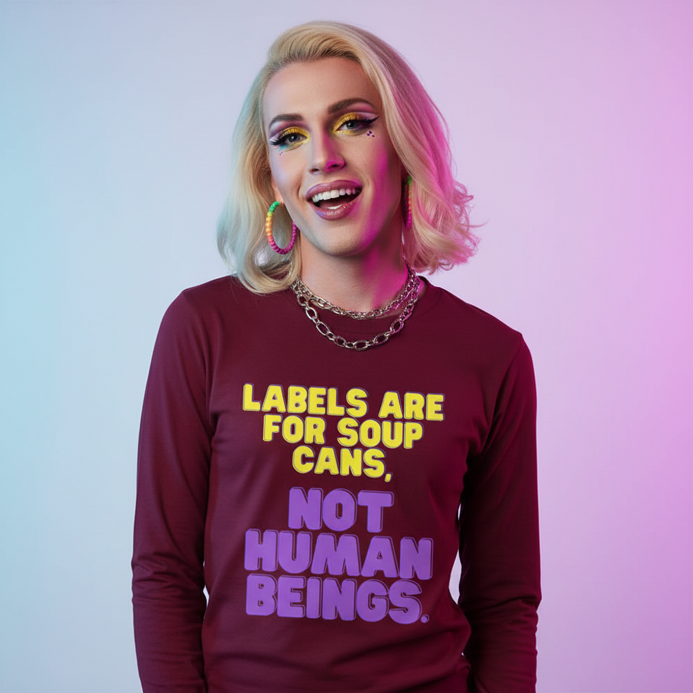 Maroon long sleeve tee reading “Labels Are For Soup Cans” in rainbow text; blond, bold queer babe grins