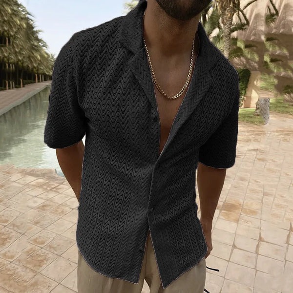 Front view of a person wearing a black textured cutout shirt by a pool