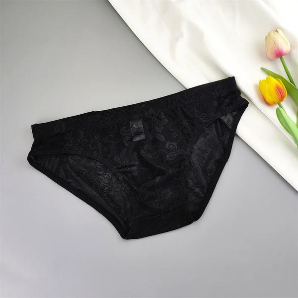 Black lace briefs laid flat beside a white cloth and colorful tulips
