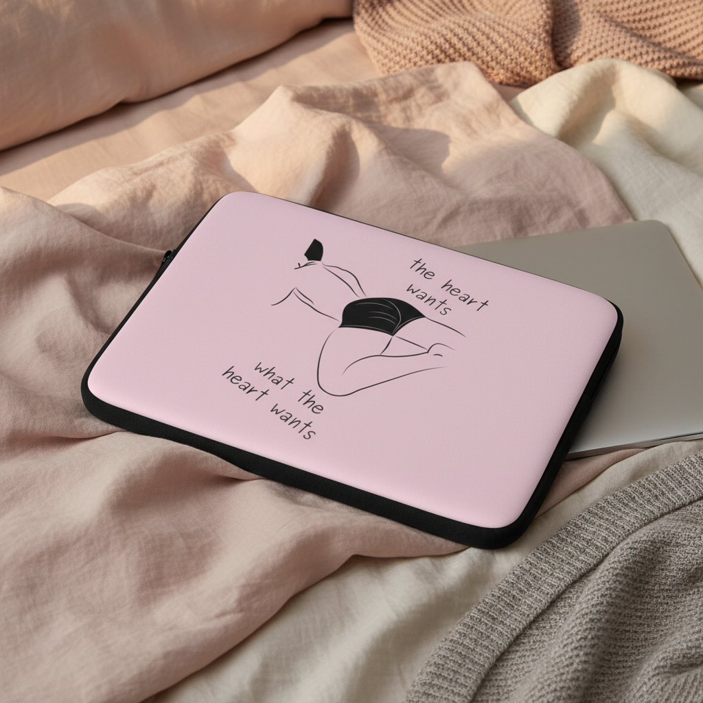 Laptop sleeve in pink neoprene with black trim, featuring a line-art femme figure in black underwear and "the heart wants what the heart wants" handwritten.