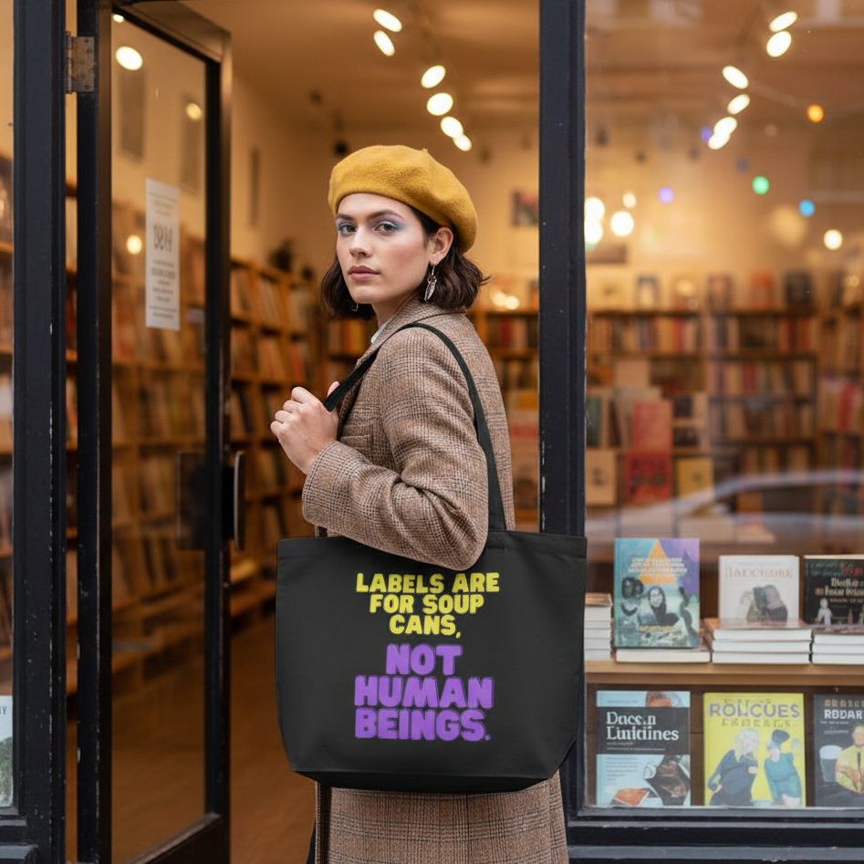 Young woman at bookstore entrance with a Labels Are For Soup Cans large organic tote bag. The tote, made from eco-conscious cotton, promotes self-expression and empowerment, embodying bold queer pride and visibility.