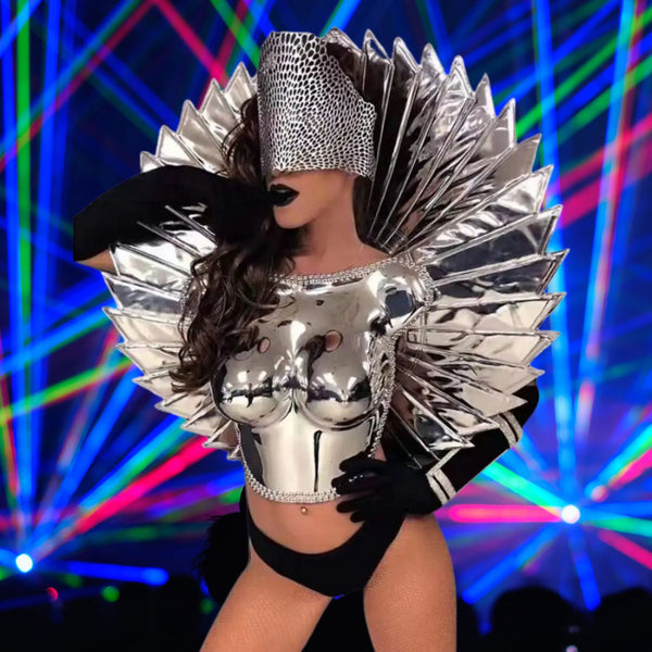 Front-facing performer in a reflective silver spiked costume, black gloves, and fishnet stockings