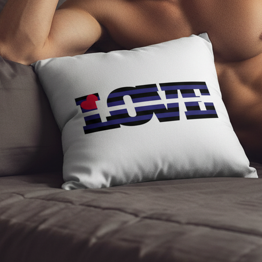 A person reclines on a couch holding a Leather Pride Love Pillow with black and blue stripes spelling “LOVE” using a red