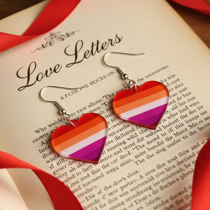 Rainbow-striped heart dangle earrings on an open “Love Letters” book with red ribbon