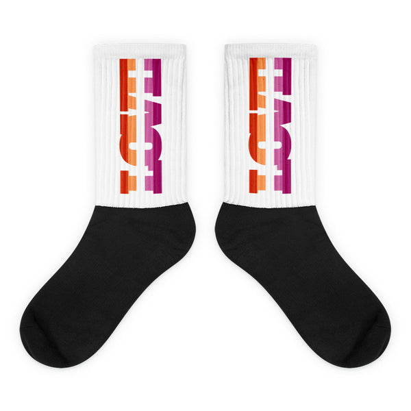 Pair of crew socks with black feet and white ribbed cuffs reading “LOVE” in orange and magenta