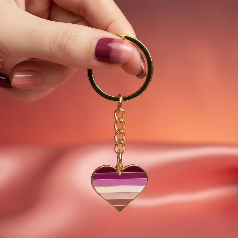 Lesbian pride heart keychain with gold-tone ring and striped enamel heart, held by a hand