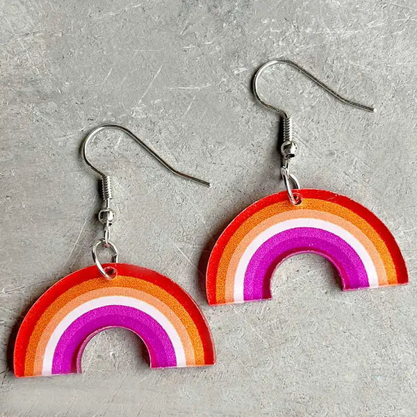 Pair of rainbow arch acrylic dangle earrings with silver hooks on a gray surface