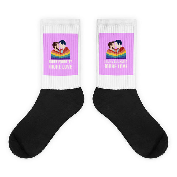 Pair of black-and-white socks with two men kissing beneath a rainbow and “MORE EQUALITY MORE LOVE” text