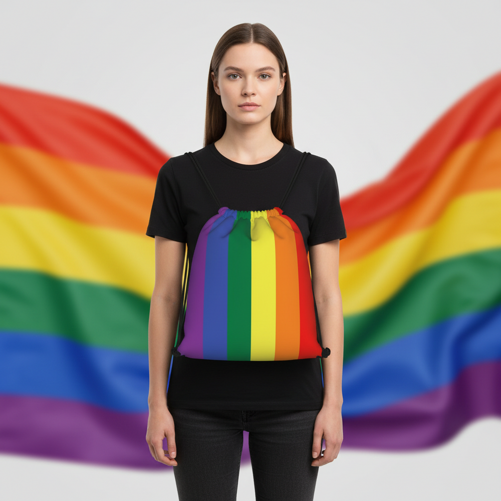 LGBT Flag Drawstring Bag with bold rainbow stripes and black cords, held by a woman; blurry rainbow Pride flag in background.