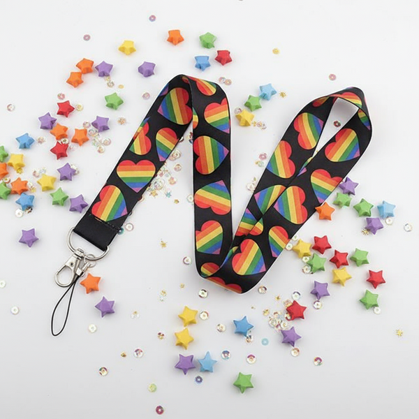 Close-up of a black lanyard with rainbow-striped heart patterns, silver clasp and wrist loop