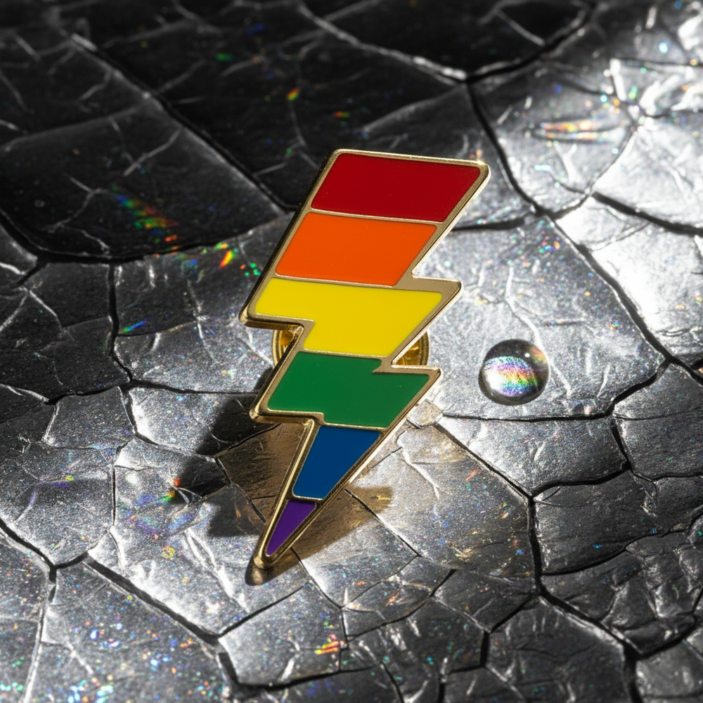 Rainbow lightning-bolt enamel pin on a reflective cracked black surface