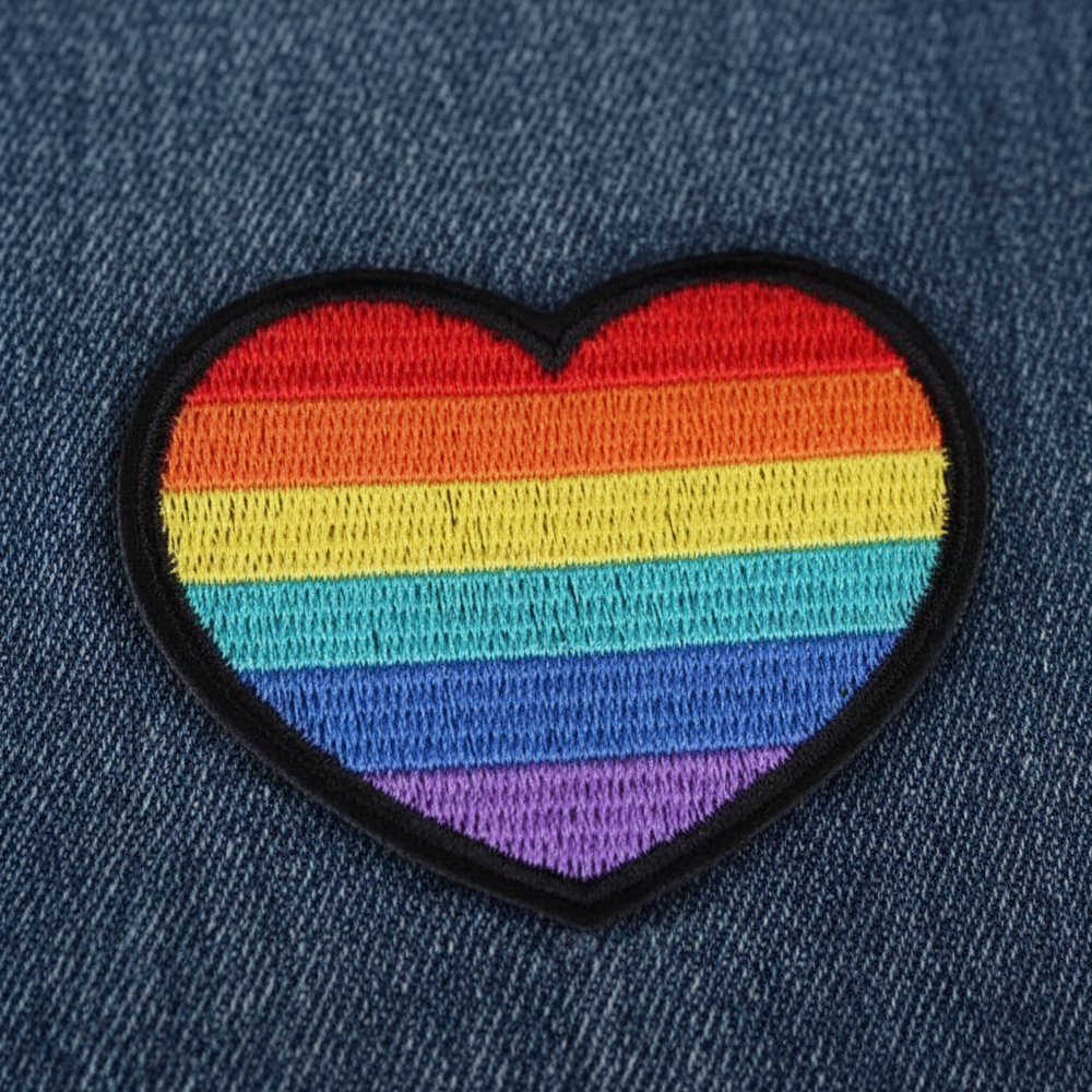 Close-up of a rainbow-striped heart embroidered iron-on patch on denim