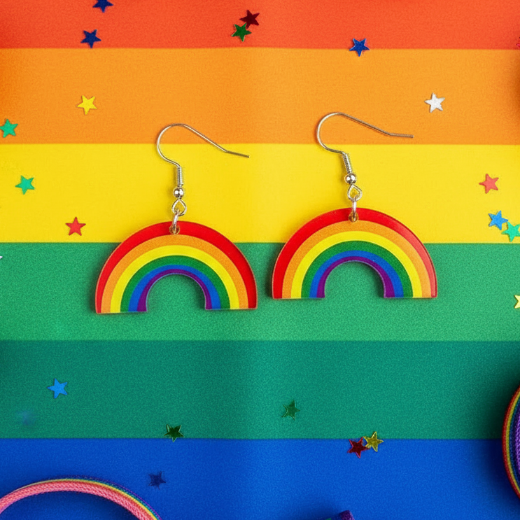 Pair of rainbow arch dangle earrings with silver hooks on a Pride flag backdrop