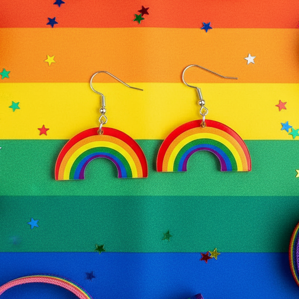 Pair of rainbow arch dangle earrings with silver hooks on a Pride flag backdrop
