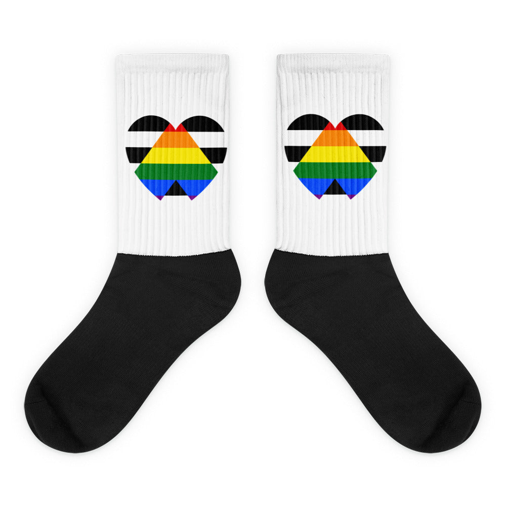 Pair of black-and-white crew socks with rainbow-striped geometric heart designs