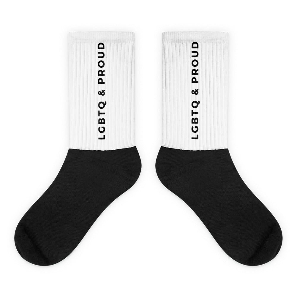 Pair of black socks with white ribbed cuffs reading “LGBTQ & PROUD” vertically