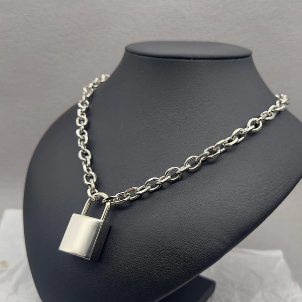 Silver chain necklace with a large rectangular padlock pendant on a black display bust