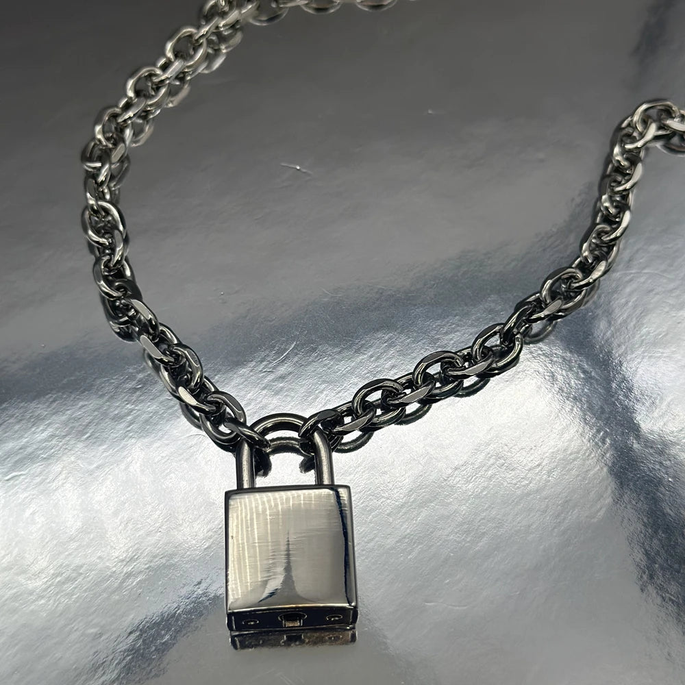 Close-up of a chunky silver chain necklace with a rectangular padlock pendant