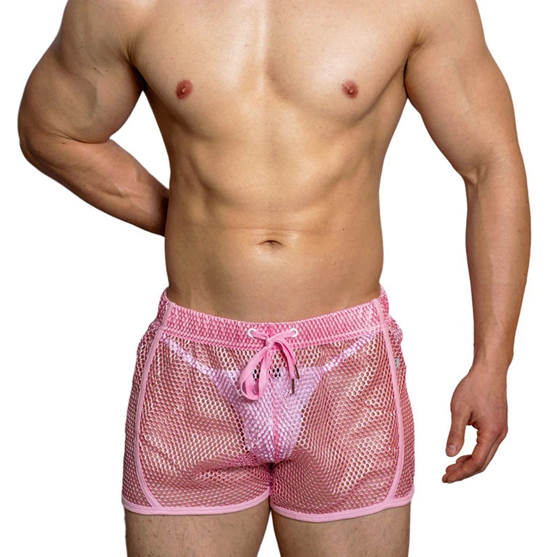 Front view of a model wearing loose pink mesh boxer shorts with a drawstring
