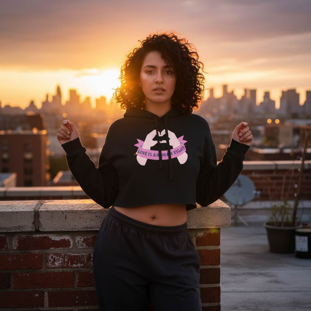 Love Is A Human Right Crop Hoodie worn by a curly-haired person at sunset on a rooftop, city lights glowing