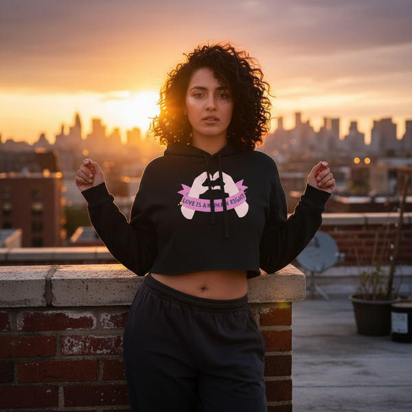 Love Is A Human Right Crop Hoodie worn by a curly-haired person at sunset on a rooftop, city lights glowing