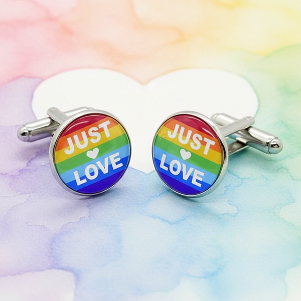 Pair of rainbow-striped round cufflinks reading “JUST ♥ LOVE” on a pastel watercolor background