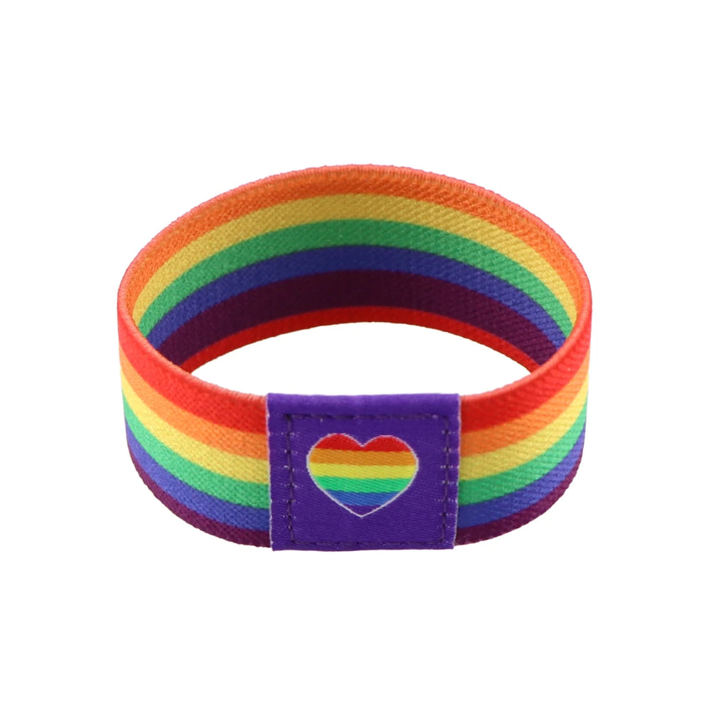 Rainbow-striped Pride wristband with a purple patch bearing a rainbow heart, shown at an angle