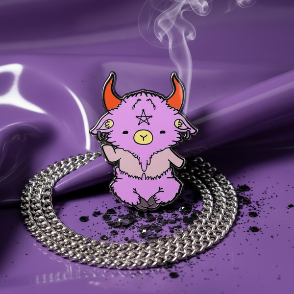 Pink goat enamel pin with orange horns and pentagram, displayed on a silver chain over purple