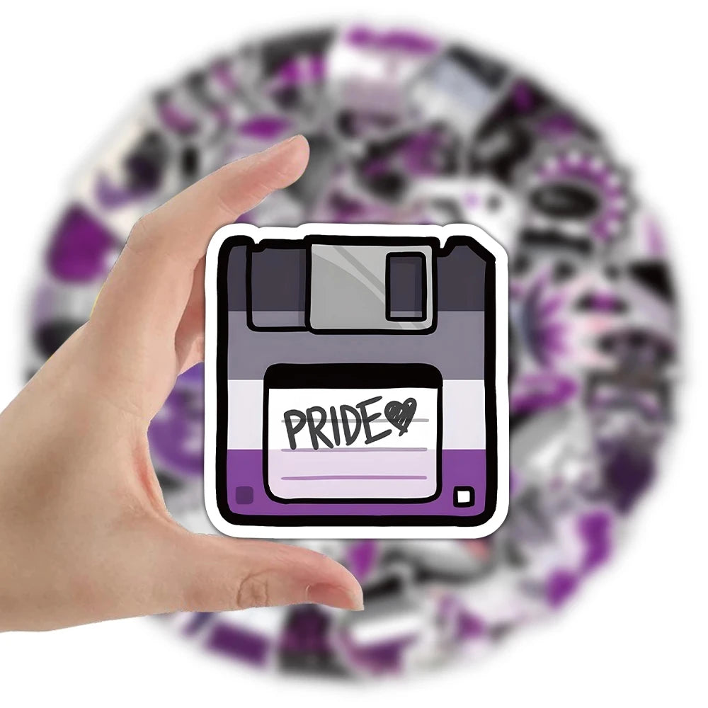 Hand holding a floppy-disk sticker in black, gray, white, and purple with “PRIDE ♥” text