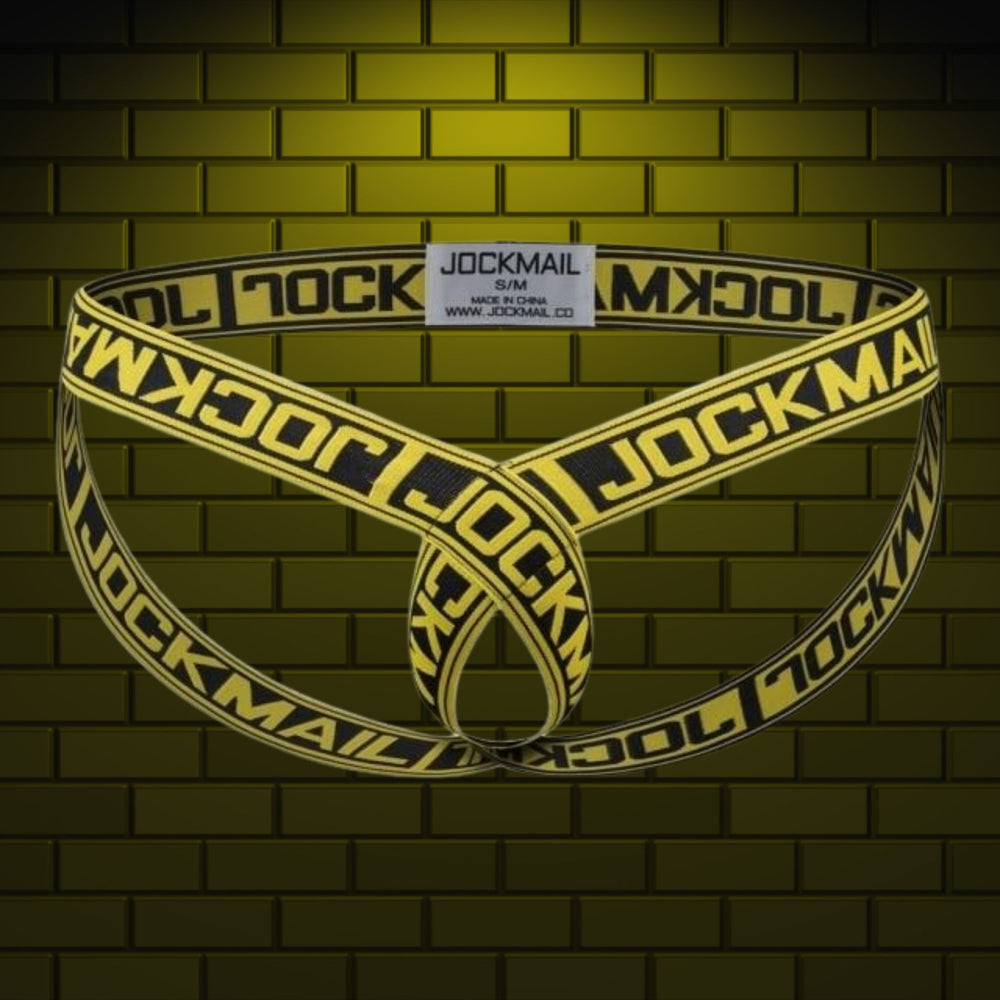 Yellow-and-black Jockmail elastic cockstrap displayed against a brick wall
