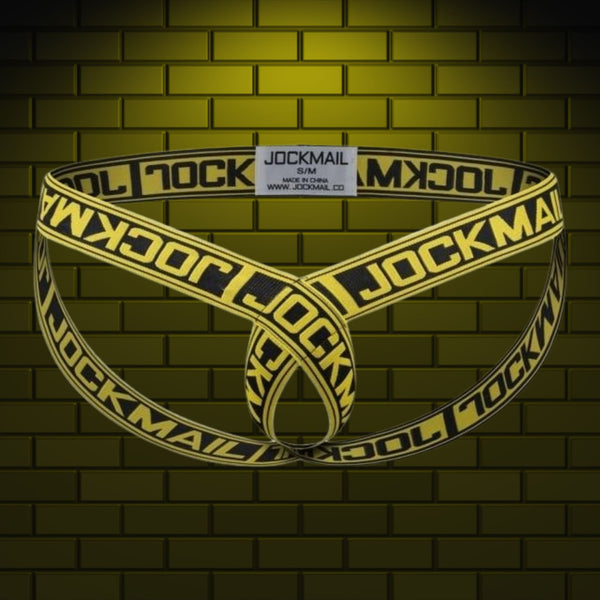 Yellow-and-black Jockmail elastic cockstrap displayed against a brick wall
