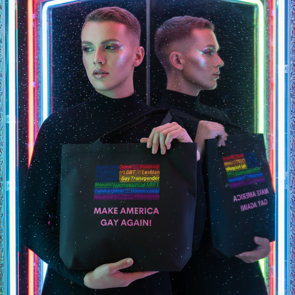 Person with glitter makeup holds a black tote reading “MAKE AMERICA GAY AGAIN!”