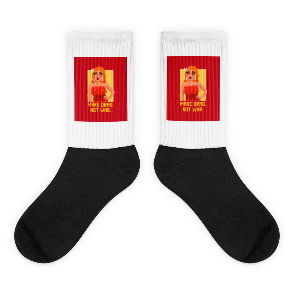 Pair of black-and-white crew socks with red panels reading “MAKE DRAG, NOT WAR.”