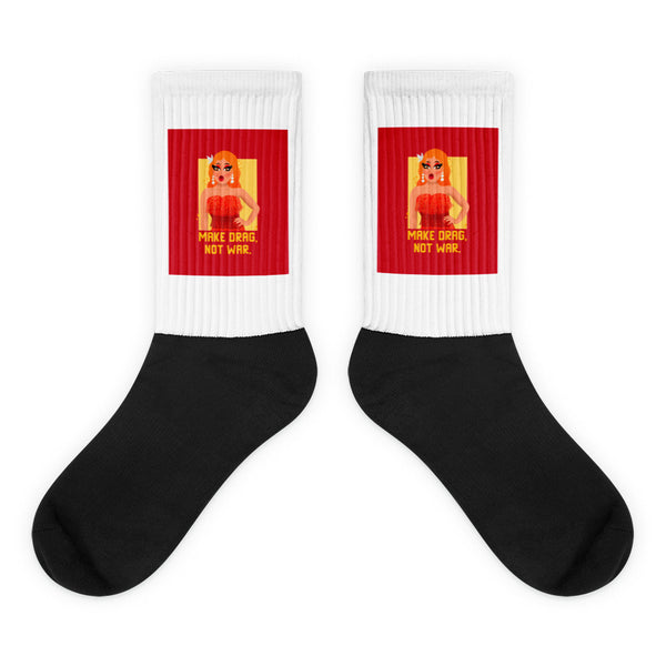 Pair of black-and-white crew socks with red panels reading “MAKE DRAG, NOT WAR.”
