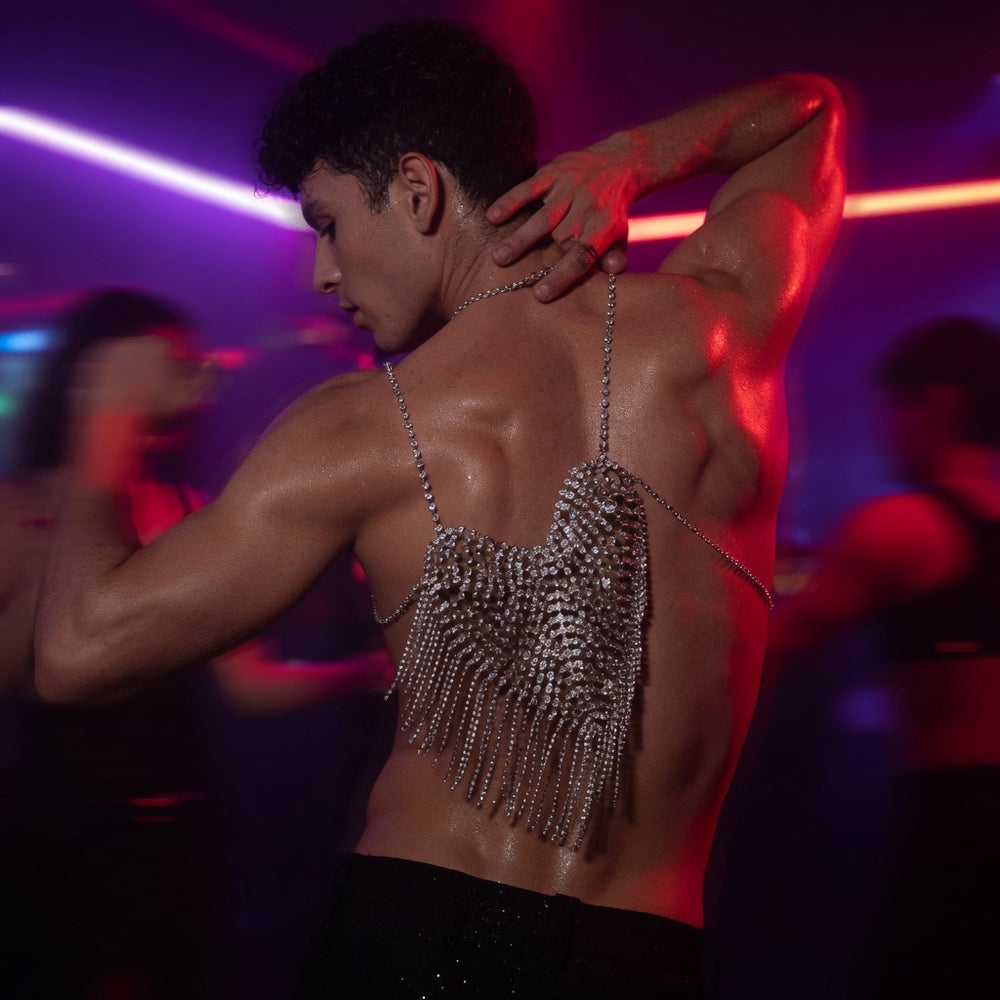 Back view of a shirtless person wearing a rhinestone chain halter top in a neon-lit club